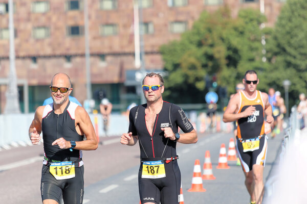 СТОКГОЛЬМ - 23 АУГ 2015: Трое мужчин в ярких солнцезащитных очках, здание позади ITU World Triathlon event в Стокгольме, 2015
