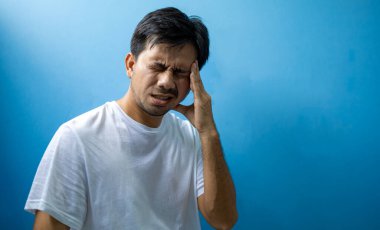 Genç Asyalı adam baş ağrısı ve migrenden muzdarip, stresli..