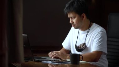 Asyalı adam ev ofisinde çalışıyor, evden çalışıyor.