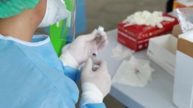 Hemşire covid-19 koronavirüs aşısı içeren şırınga ve şişeyi iğneye hazır tutuyor..