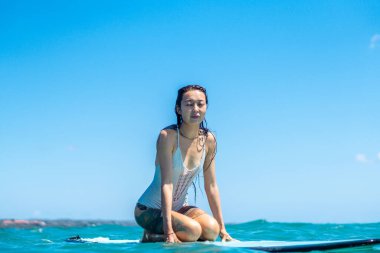 Mavi okyanusta sörf tahtasındaki sörfçü kızın portresi Bali 'deki sudan çekilmiştir.