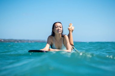 Mavi okyanusta sörf tahtasındaki sörfçü kızın portresi Bali 'deki sudan çekilmiştir.