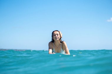 Mavi okyanusta sörf tahtasındaki sörfçü kızın portresi Bali 'deki sudan çekilmiştir.