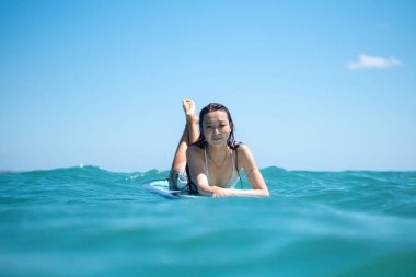 Mavi okyanusta sörf tahtasındaki sörfçü kızın portresi Bali 'deki sudan çekilmiştir.