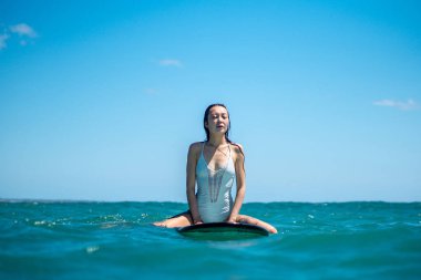 Mavi okyanusta sörf tahtasındaki sörfçü kızın portresi Bali 'deki sudan çekilmiştir.