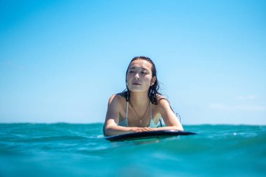 Mavi okyanusta sörf tahtasındaki sörfçü kızın portresi Bali 'deki sudan çekilmiştir.