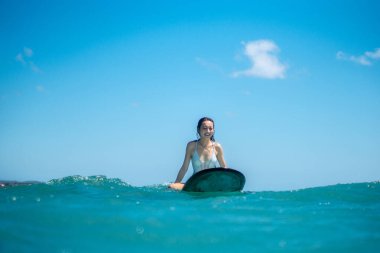Mavi okyanusta sörf tahtasındaki sörfçü kızın portresi Bali 'deki sudan çekilmiştir.