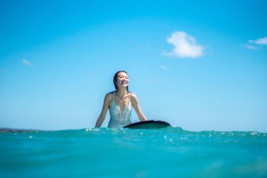 Mavi okyanusta sörf tahtasındaki sörfçü kızın portresi Bali 'deki sudan çekilmiştir.