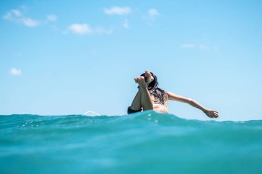 Mavi okyanusta sörf tahtasındaki sörfçü kızın portresi Bali 'deki sudan çekilmiştir.