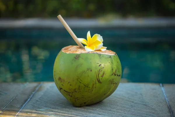 バリ島のプールの端にある竹の藁と熱帯の花のフランジパニと緑の若いココナッツが閉じます — ストック写真