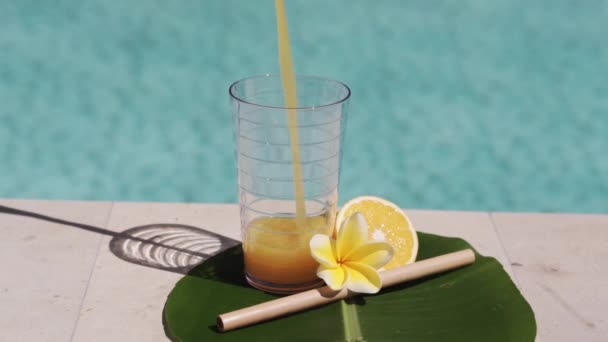 有橙汁 一半新鲜橙子 黄色乳酪花和气泡蓝色游泳池背景的玻璃杯视频镜头 — 图库视频影像