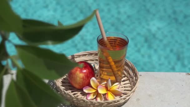 Videofilmer Glas Med Äppeljuice Bambuhalm Rött Äpple Tropisk Blomma Frangipani — Stockvideo