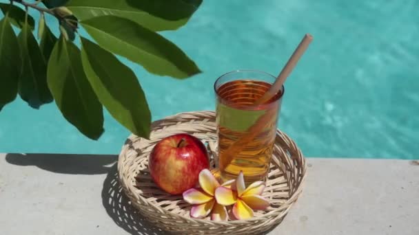 Videofilmer Glas Med Äppeljuice Bambuhalm Rött Äpple Tropisk Blomma Frangipani — Stockvideo