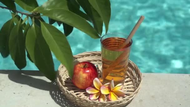 Videofilmer Glas Med Äppeljuice Bambuhalm Rött Äpple Tropisk Blomma Frangipani — Stockvideo