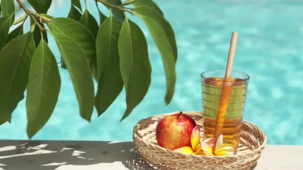 玻璃与苹果汁 红苹果 热带花卉 绿叶树枝和泡沫蓝色游泳池背景视频镜头 — 图库视频影像