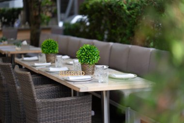 Plaket bir açık hava kafe veya restoranının servis masasında tutuluyor. Sığ alan derinliği, bulanık arkaplan
