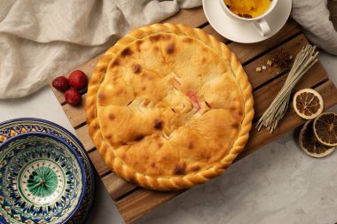 Geleneksel desenli dekoratif ulusal Özbek seramik tabaklarının yanında çilekli sıcak Osetya turtası. Çay için klasik oryantal hamur işleri..