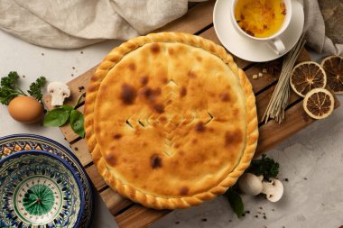 Geleneksel desenli dekoratif ulusal Özbek seramik tabaklarının yanında mantar dolgulu sıcak Osetya turtası ve bitkiler. Çay için klasik oryantal hamur işleri.