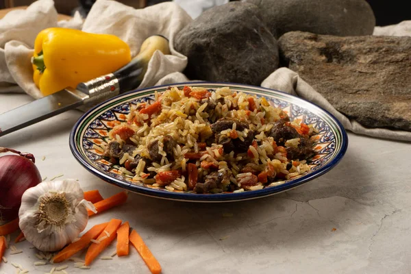 Geleneksel bir desenle dekoratif ulusal Özbek tabağında kuzu veya biftekli sıcak pilav. Haşlanmış pirinç, et ve baharatlı sebzelerden yapılmış klasik bir doğu yemeği..