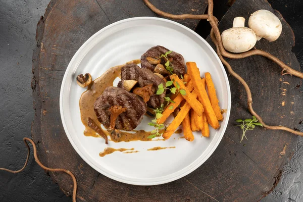 Grilled beef medallions with a side dish of sweet potatoes and mushroom sauce of mushrooms. main hot meat dish. Veal or pork steak.