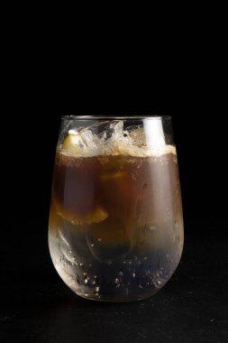 Espresso toniği. Soğuk alkollü kahve kokteyli ve siyah arka planda şeffaf bardakta ferahlatıcı bir tonik..