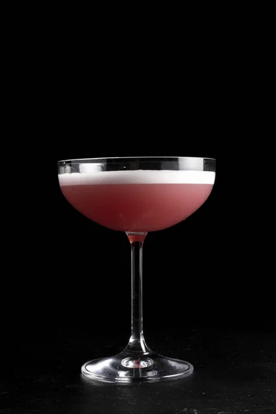 Clover Kulübü kokteyli. Soğuk alkollü bıldırcın yumurtası proteini, limon suyu, ahududu şurubu ve siyah arka planda şeffaf bardakta cin..