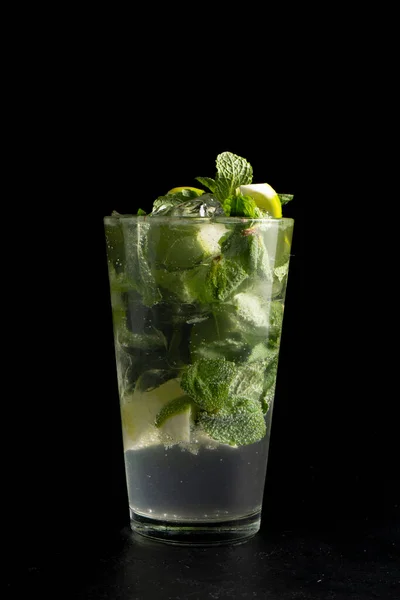 Mojito kokteyli. Soğuk alkollü limon, nane, şeker şurubu, beyaz rom, soda ve buz karışımı siyah arka planda şeffaf bir bardakta..