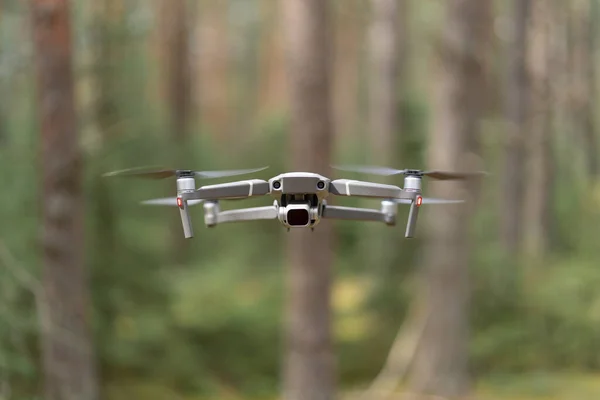 ND filtresi havada asılı duran kameralı dron kuadkopteri. Ormanda insansız hava aracı var. Sığ alan derinliği, bulanık arkaplan.