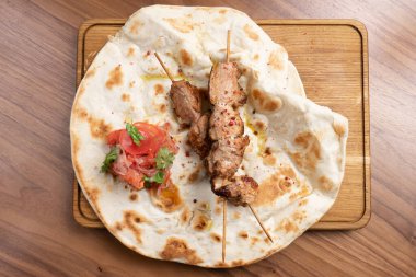Domatesli biftek kebabı, soğan ve tahta kesme tahtasının üzerinde taze pişmiş tortilla. Geleneksel Doğu helal et yemeği, ızgarada dana eti veya kuzu eti..