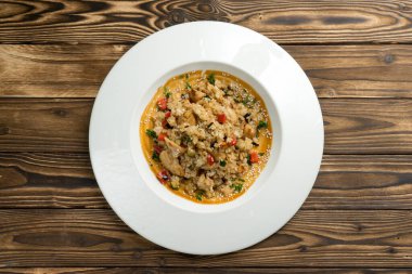 Tavuk göğsü, kırmızı biber ve üzerine susam tohumu serpiştirilmiş tatlı ve ekşi soslu diğer sebzeler. Ahşap mutfak masasında beyaz seramik tabakta sıcak bir Asya tabağı. Üst görünüm