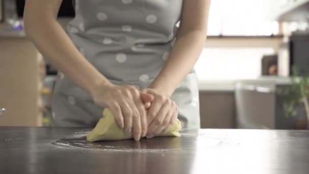 Młoda kobieta ugniata ciasto na stole kuchennym — Wideo stockowe