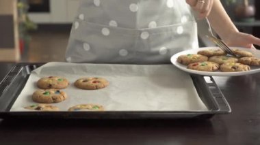 Bir kadın renkli M & M şekerli kurabiyeleri pişirme tepsisinden çıkarır
