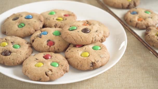 Ciasteczka z kolorowymi cukierkami M & M są usuwane z tacy na talerzu — Wideo stockowe