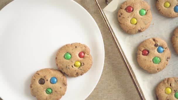 A woman removes a cookie with M&Ms chocolates from a baking tray with a spatula — Stockvideo