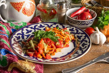Geleneksel Özbek desenli bir tabakta fırında patlıcan, domates, havuç ve dolma biber salatası.