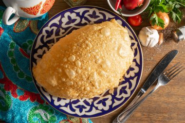 Geleneksel Özbek desenli bir tabakta sığır eti, kuzu eti, domuz eti veya tavuk ile doldurulmuş Cheburek.