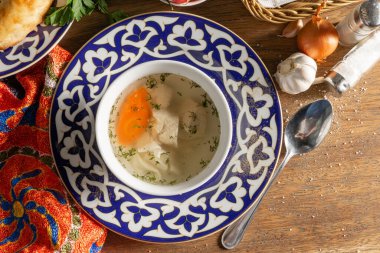 Tovuk Shurpa çorbası. Geleneksel Özbek süslemeleri olan bir tabakta ev yapımı erişte ve havuç ile tavuk göğsü çorbası.
