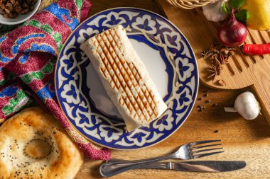 Shawarma, geleneksel Özbek aksesuarlarıyla altın kahverengiye kadar ızgara yapıyor.