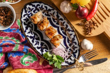 Geleneksel Özbek desenli, kırmızı soğanlı ve maydanozlu ev yapımı sosislerden yapılan küçük bir porsiyon şiş kebap.