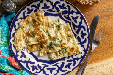 Geleneksel Özbek yemeği içinde yeşil soğanlı omlet. Sıcak kahvaltı tabağı yumurta, süt ve otlar.