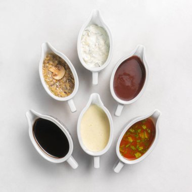 Beyaz mermer bir masanın üzerinde seramik tabaklar içinde birkaç farklı oryantal sos. Ketçap, soya sosu, çiftlik sosu, peynir sosu, barbekü sosu ve mantar sosu.