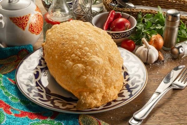 Geleneksel Özbek desenli bir tabakta sığır eti, kuzu eti, domuz eti veya tavuk ile doldurulmuş Cheburek.