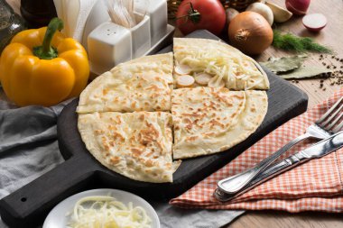 Tahta kesme tahtasının üzerinde sosisli ve mozzarella peynirli düz ekmek.