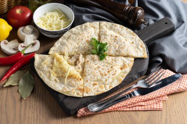 Mozarella peynirli tortilla ve tahta kesme tahtasındaki tavuk.