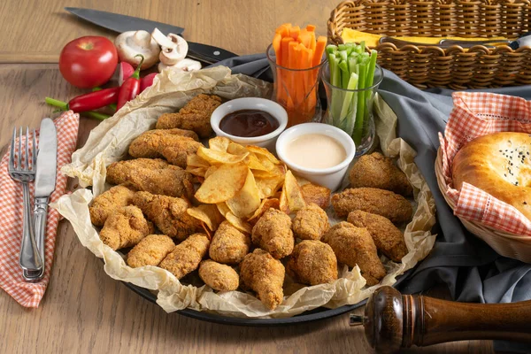 Patates cipsi soslu ve sebzeli büyük bir tabak kızarmış tavuk kanadı.