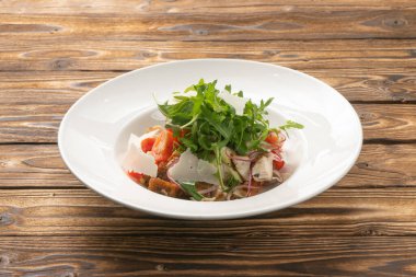 Domatesli sebze salatası roka, tavuk, parmesan peyniri ve beyaz seramik tabakta çavdar ekmeği.