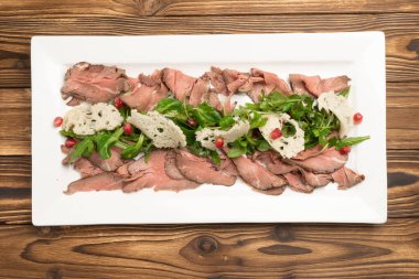 Beyaz seramik tabakta roka ve nar ile rosto.