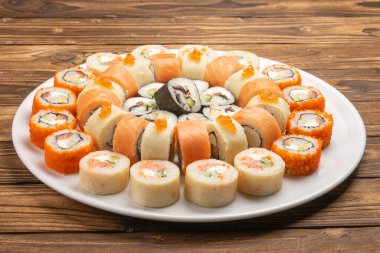 Büyük, güzel suşi seti. Somon, yılan balığı, nori, pirinç, kırmızı havyar ve beyaz yuvarlak bir tabakta avokado.