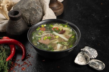 Köfteli çorba, erişte ve sebze. Koyu taş mutfak masasında.