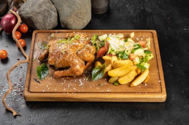 Fırında tavuk turşusu, patates ve taze sebzeyle ahşap kesim tahtasının üzerinde.